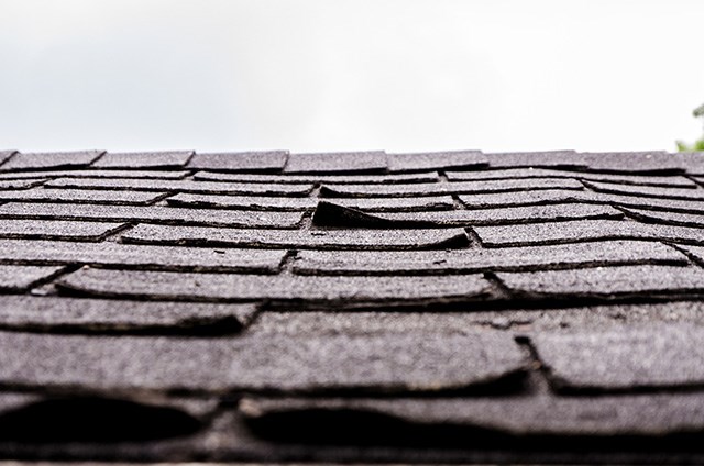 Loose shingles on asphalt residential roof in need of roof repair